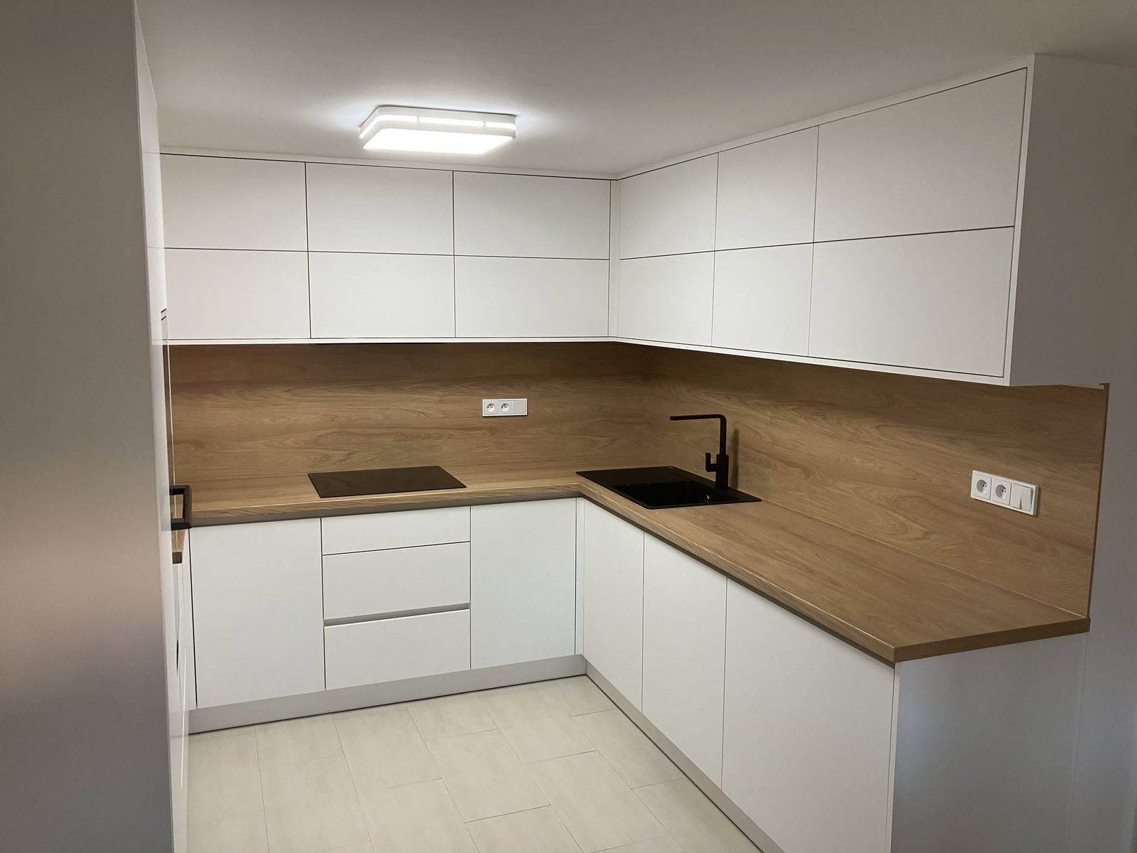 Bezúchytková bílá kuchyň s dřevěnou pracovní deskou — truhlář Plzeň a Praha
